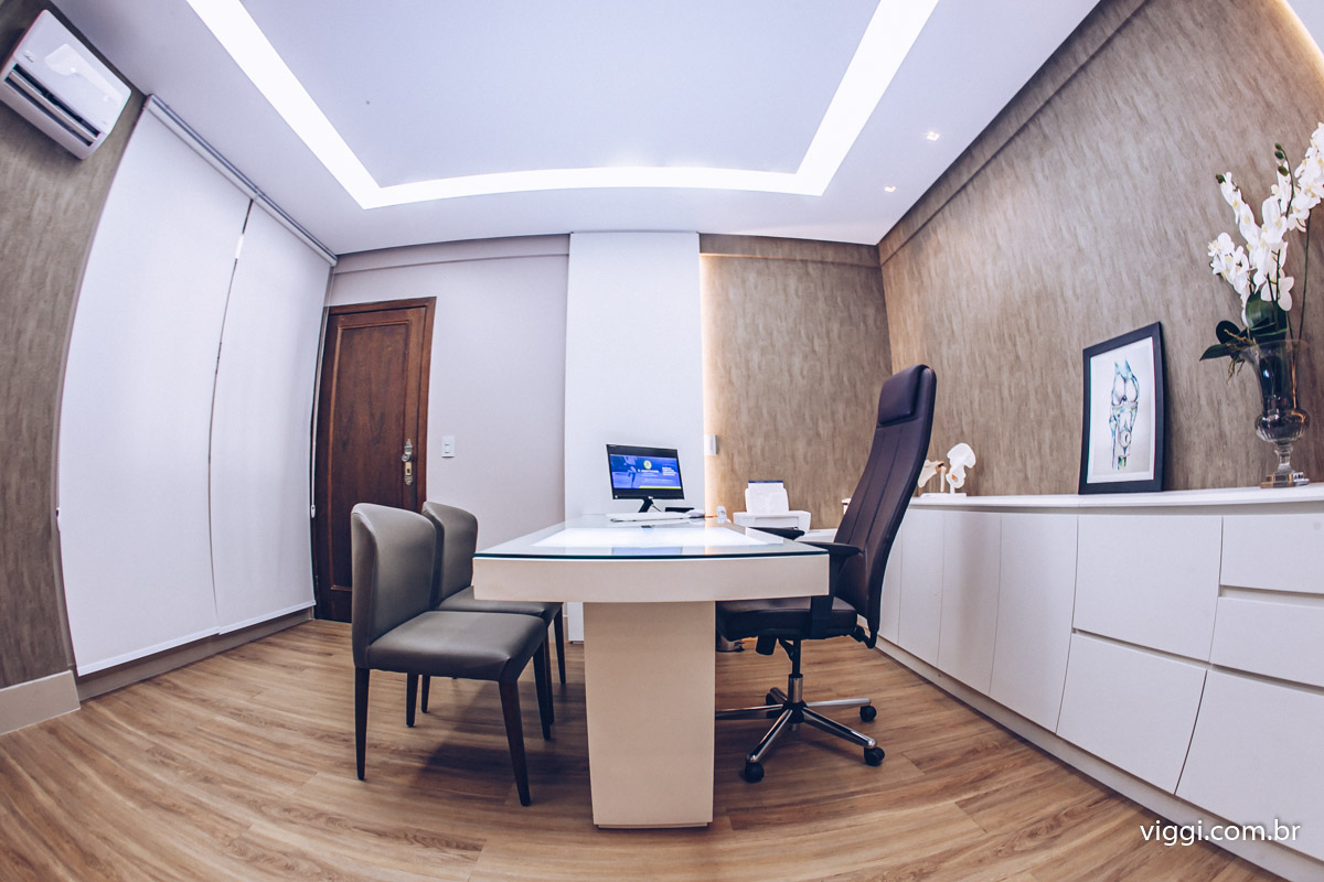Consultório médico com mesa de atendimento e decoração em tons neutros