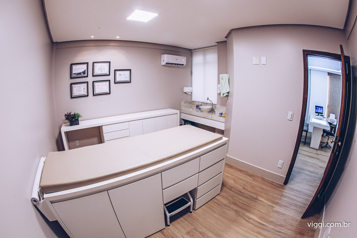 Sala de exame do consultório, com maca e certificados na parede